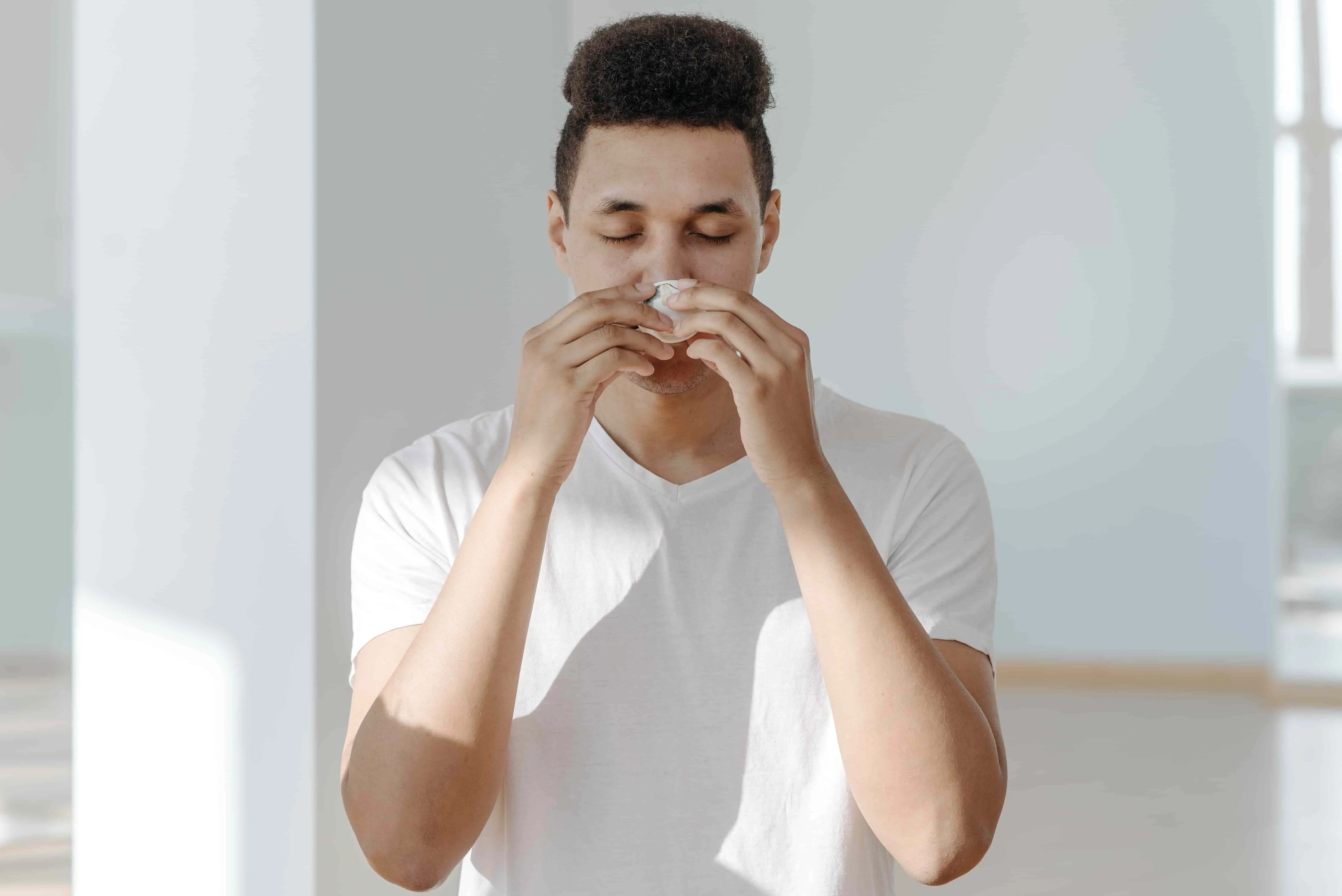 Man sneezing into tissue from allergy